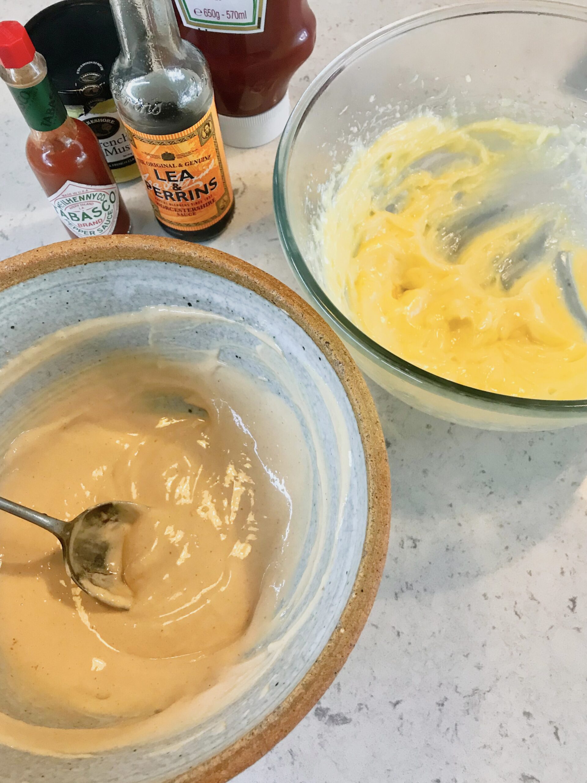 Blinis and mayonnaise mixture in bowls on a kitchen countertop.