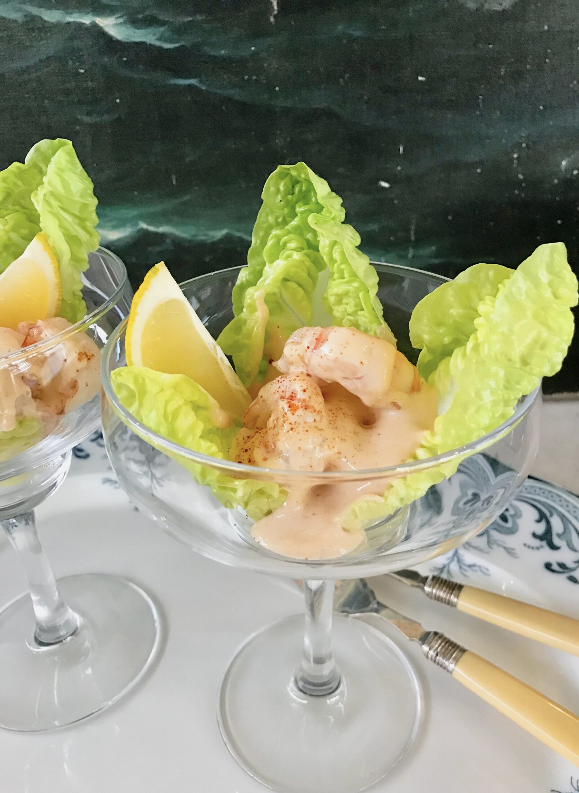 Blinis, mayonnaise and prawn cocktail in a glass on a plate.