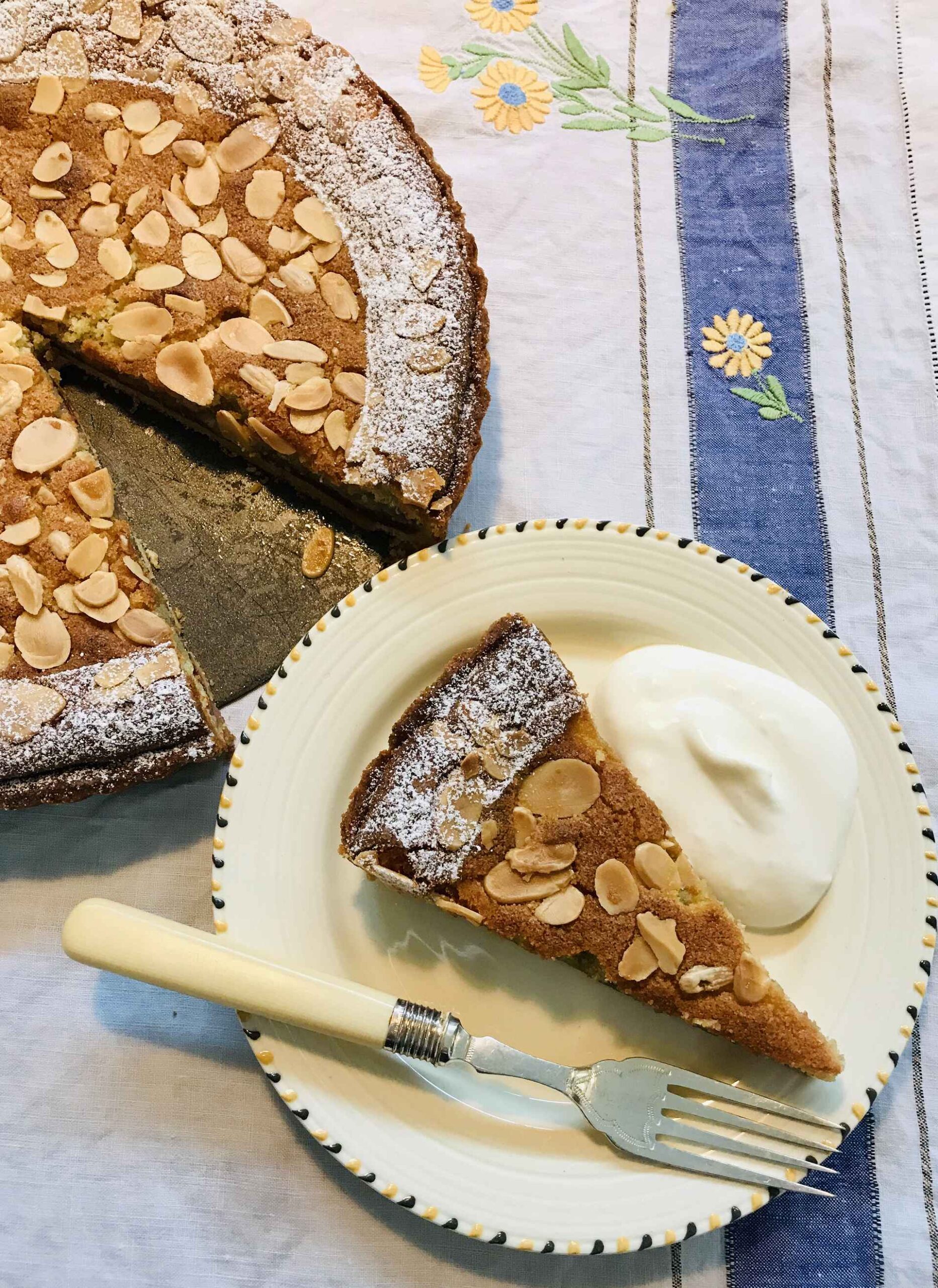 Bakewell tart on a sideplate with whipped cream.