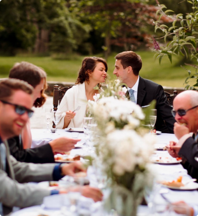 Wedding couple eating with family and friends at a long table.