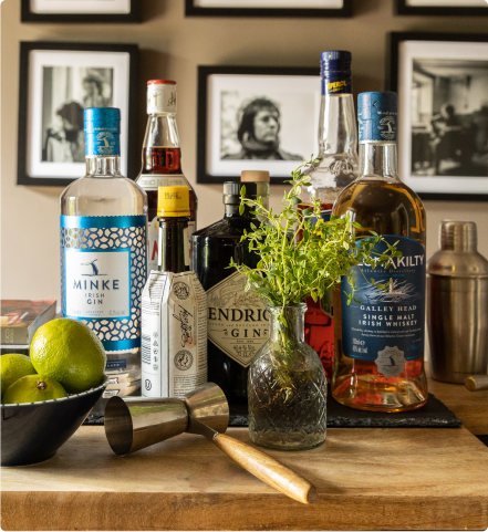 Bottles, a plant and fruits on a wooden table.