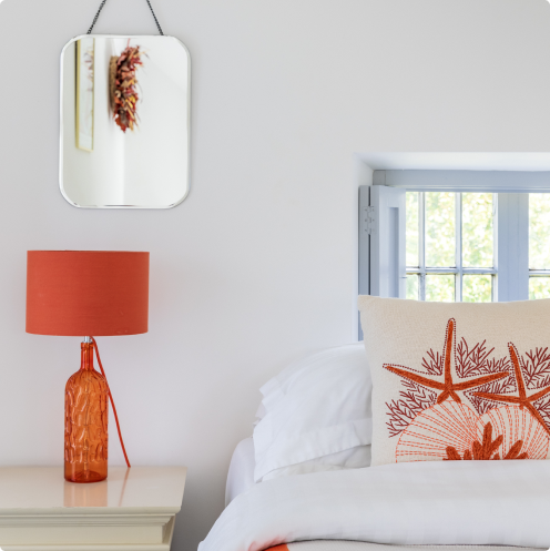 Dunowen room with a white and orange bed, orange lamp beside the bed.