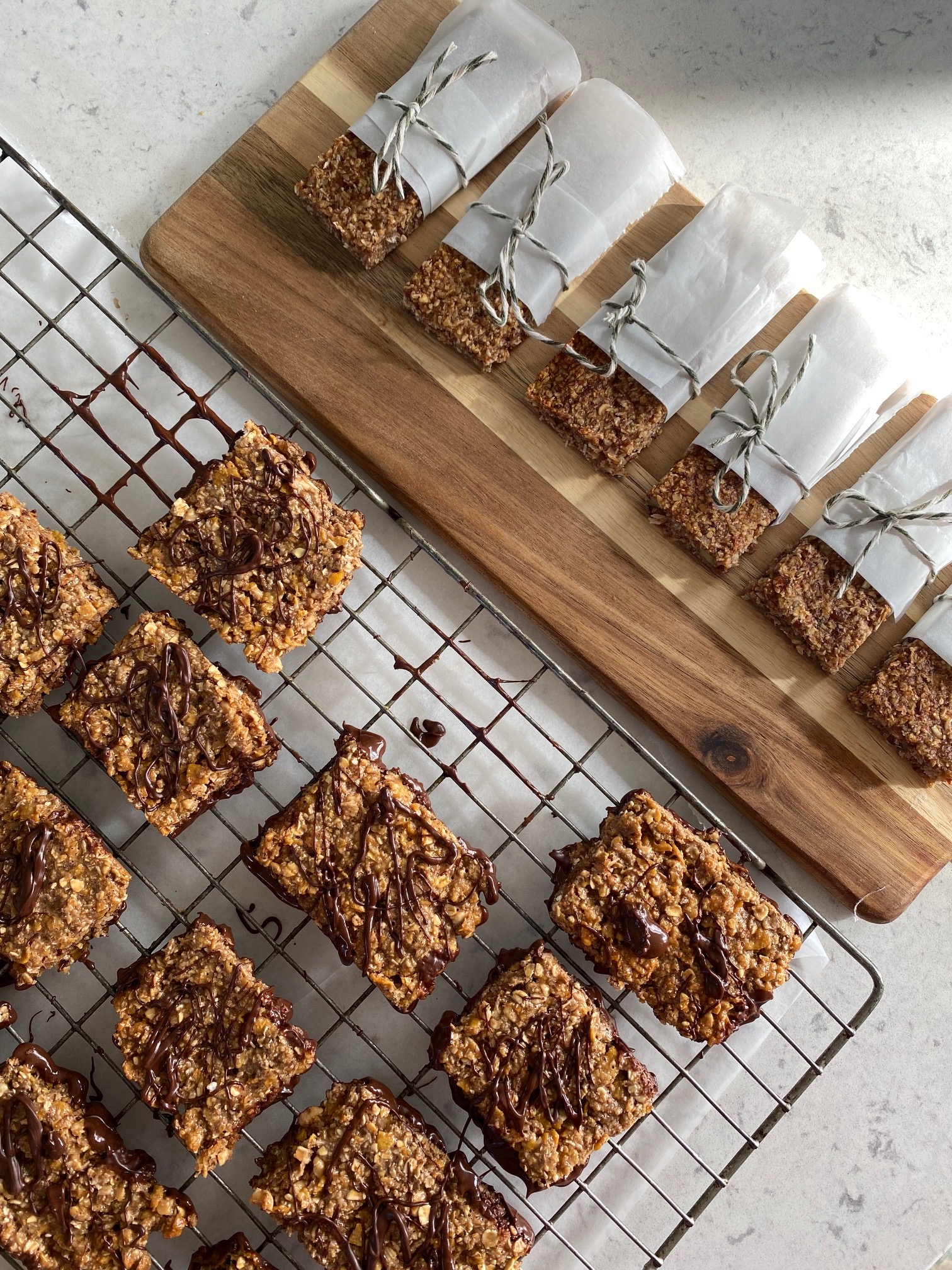 Snack bars on a rack next to Snack bars on a wooden plate wrapped in paper.