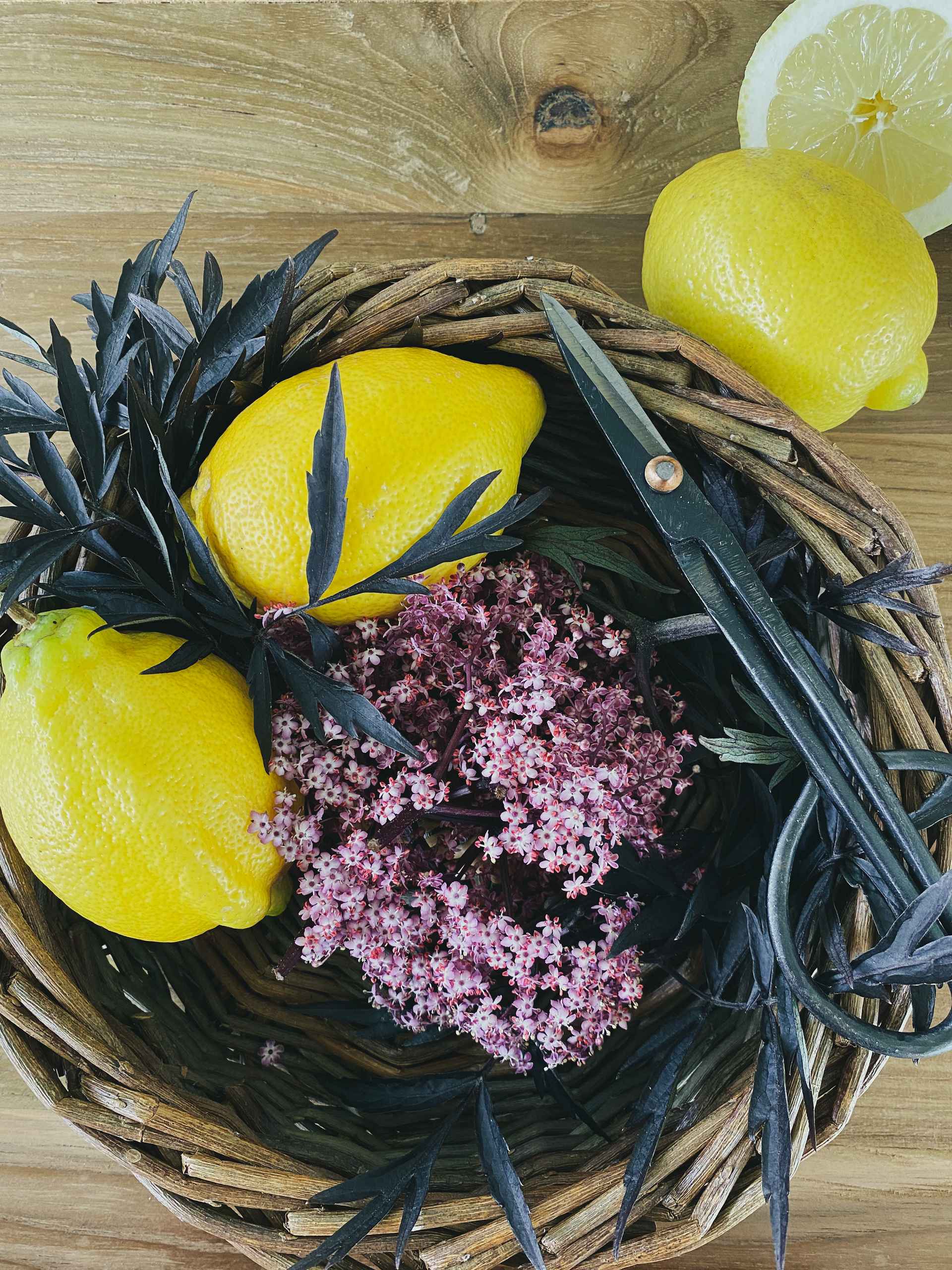 Elderflower and lemons in a wooden bowl.