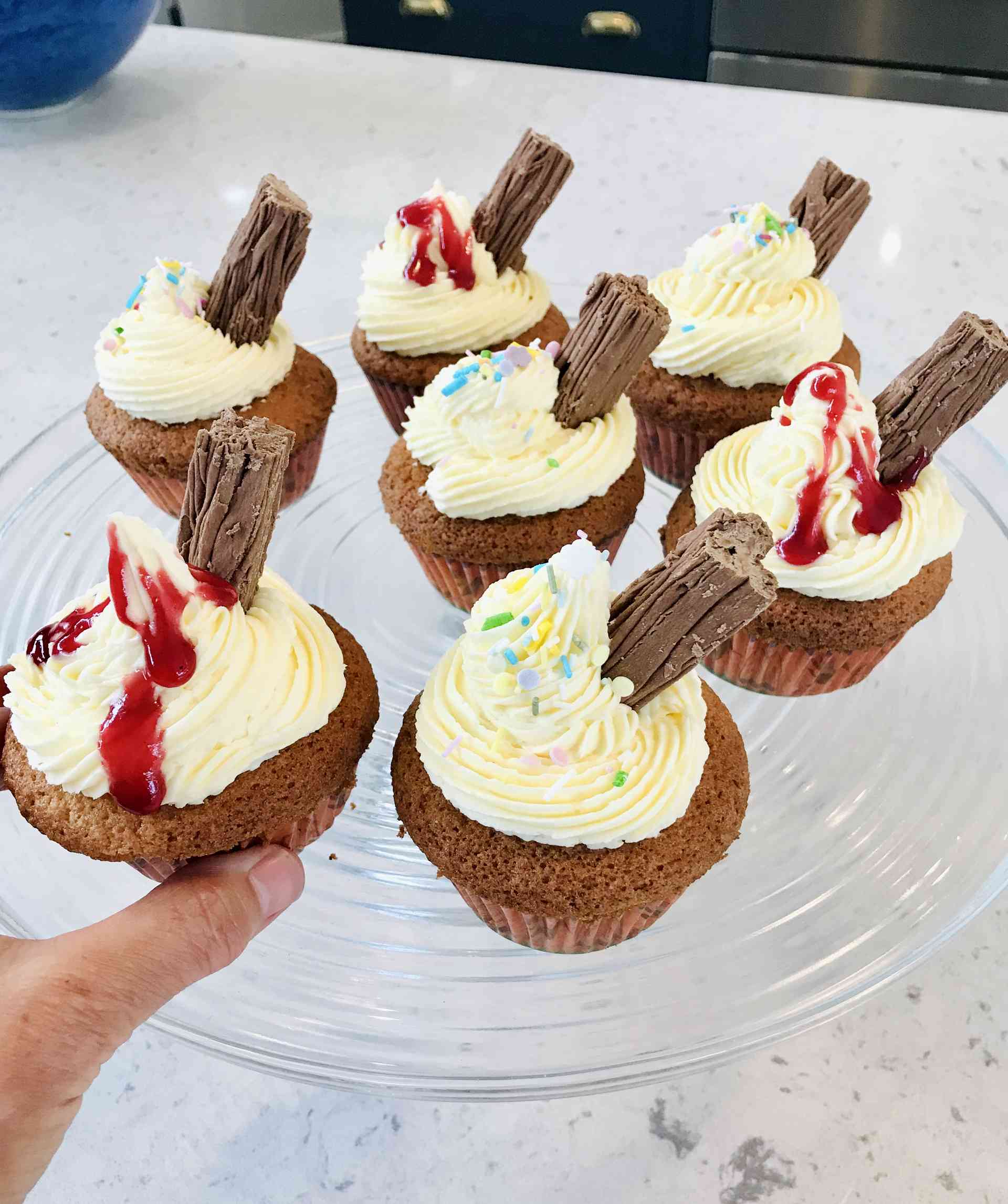 Seven decorated "99" cupcakes on a plate on a kitchen countertop.