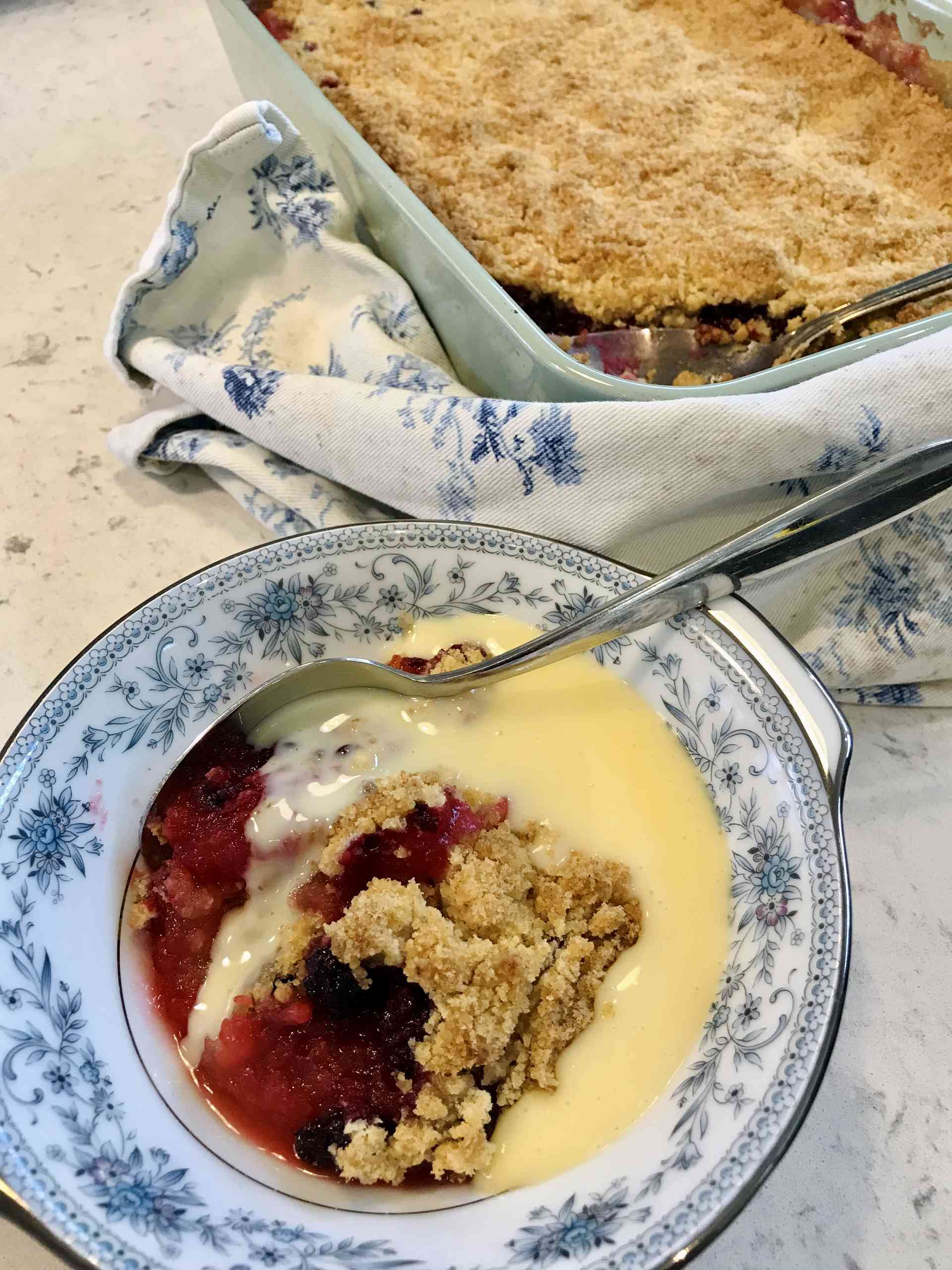 Blueberry and apple mixture in a bowl next to the cake on a kitchen countertop.