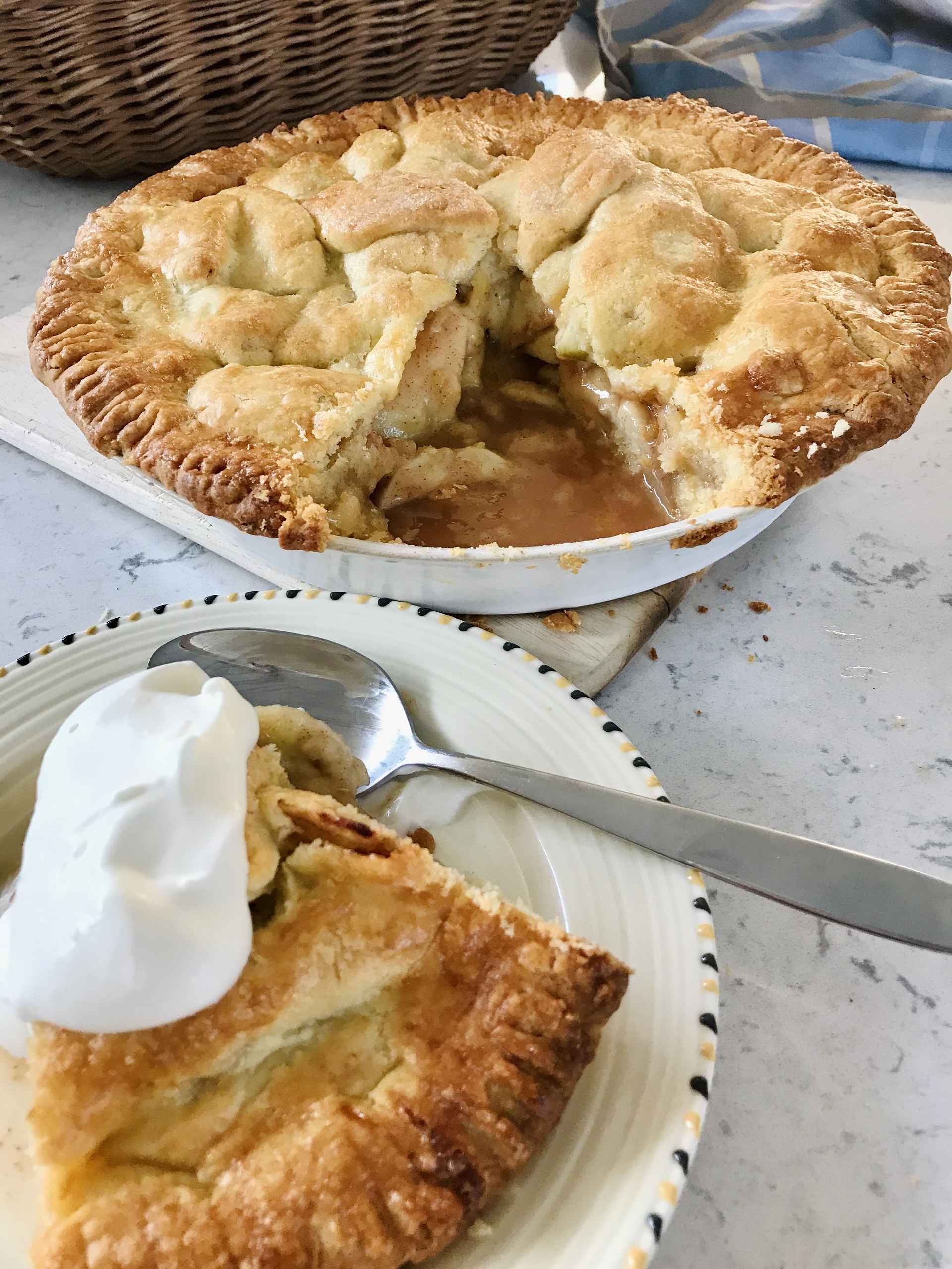 Apple pie on a plate and a slice on a sideplate.