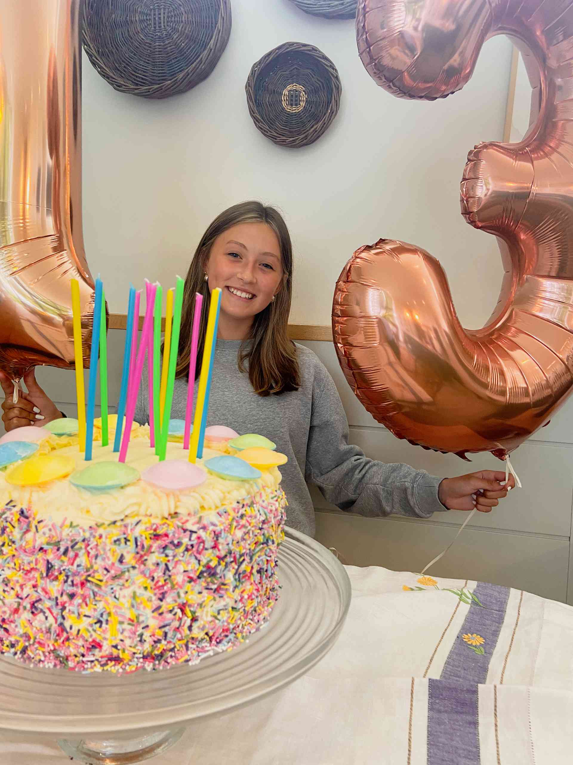 Party cake on a plate with birthday girl behind.