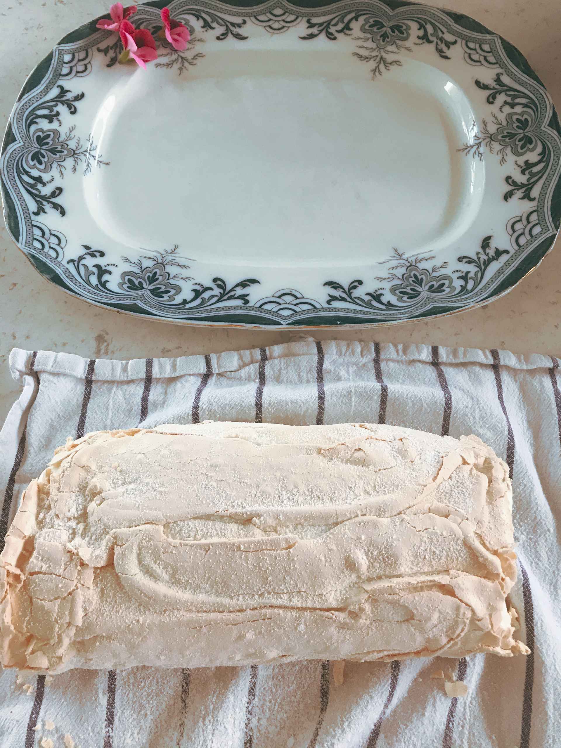 Meringue Roulade on a towel with a plate next to it.