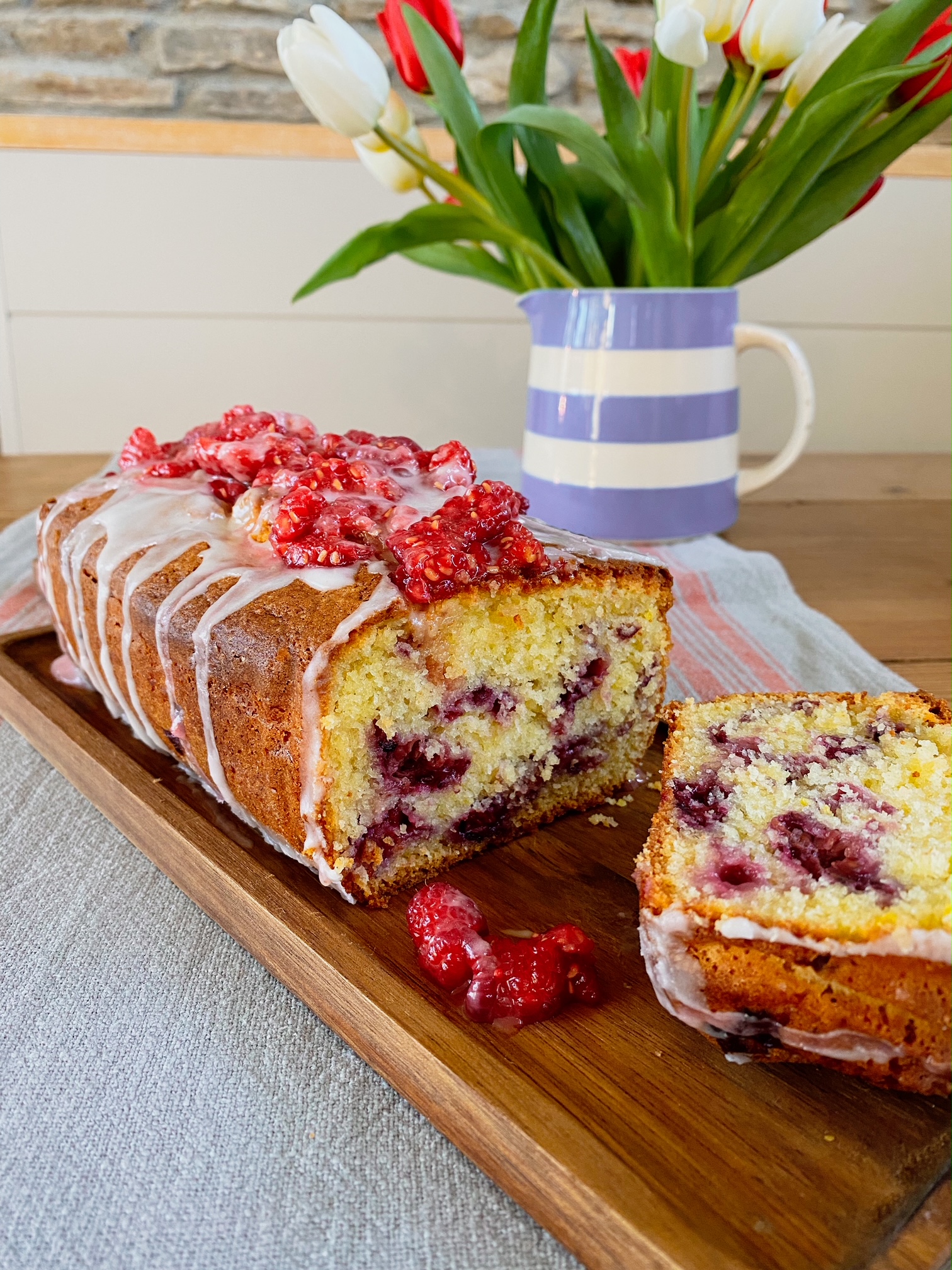 Zesty Raspberry Buttermilk Cake cut open on a wooden plate.