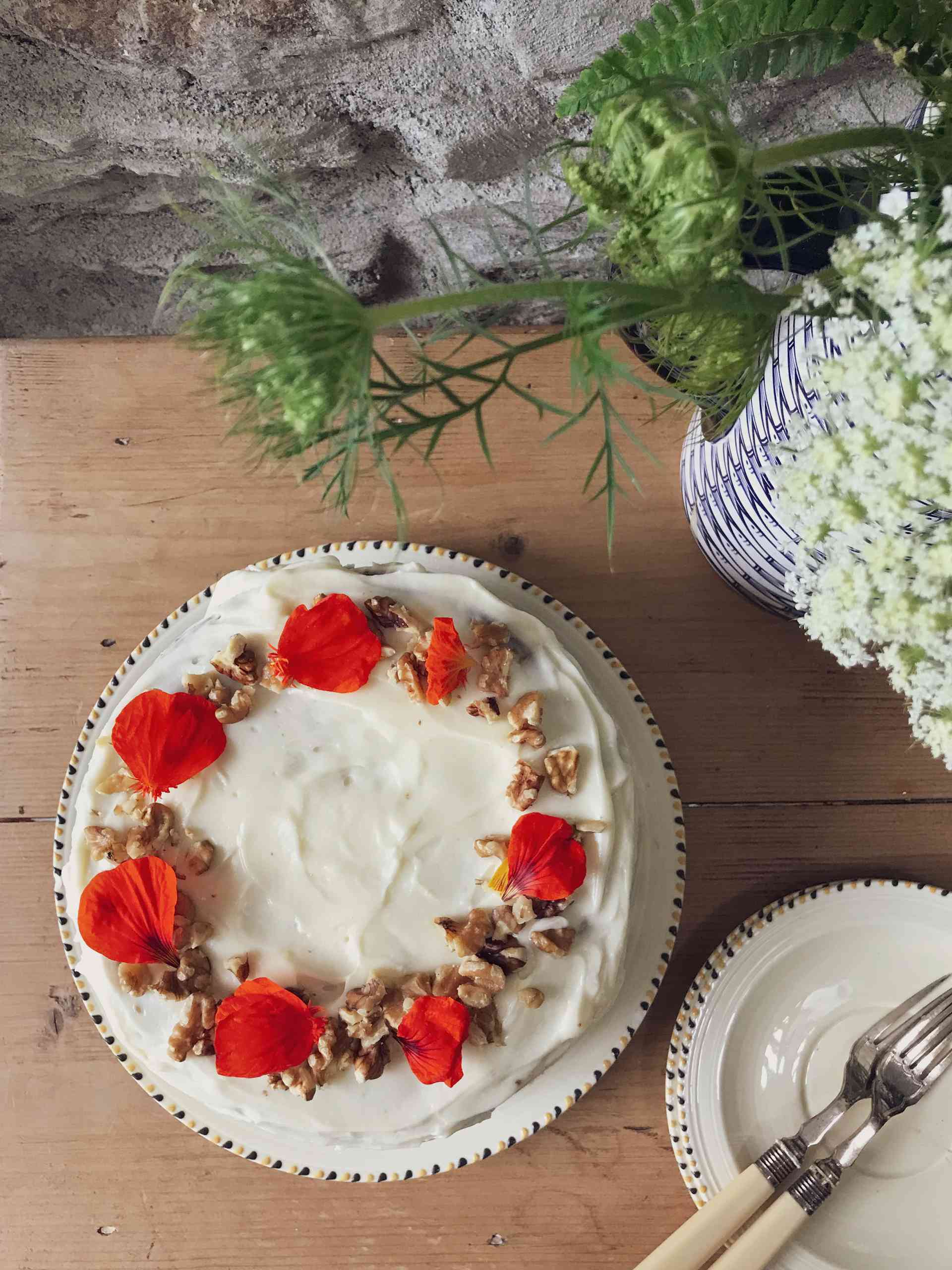 Top view of a Carrot cake on a plate with a sideplate next to it.