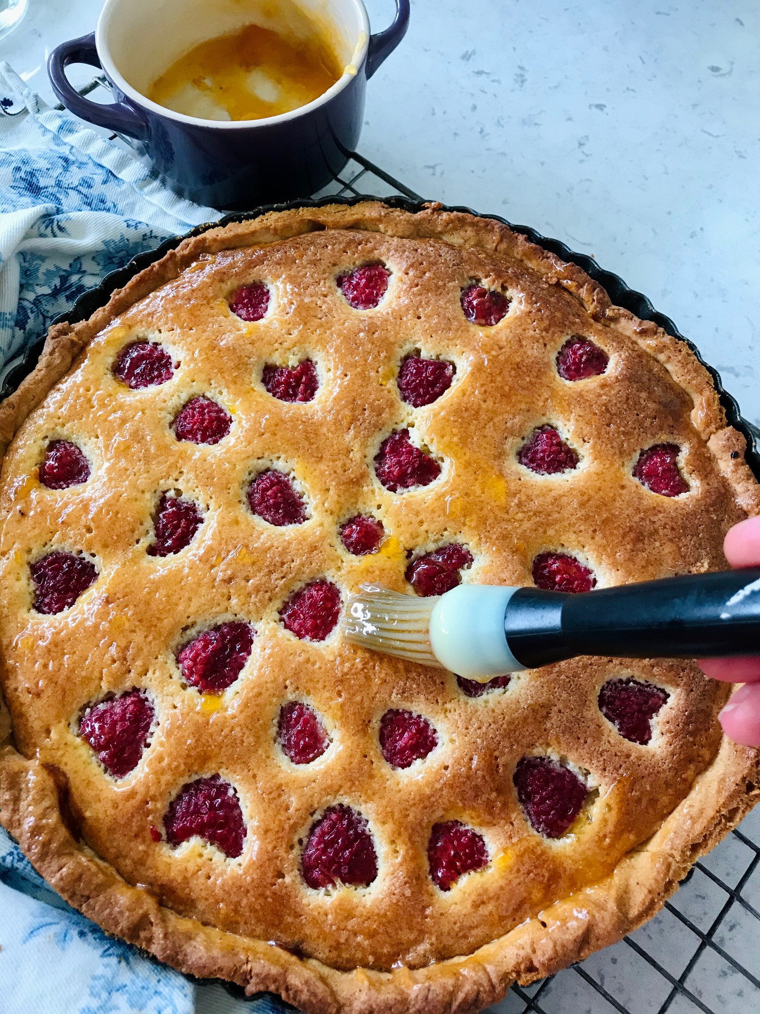 Raspberry frangipane tart on a rack.