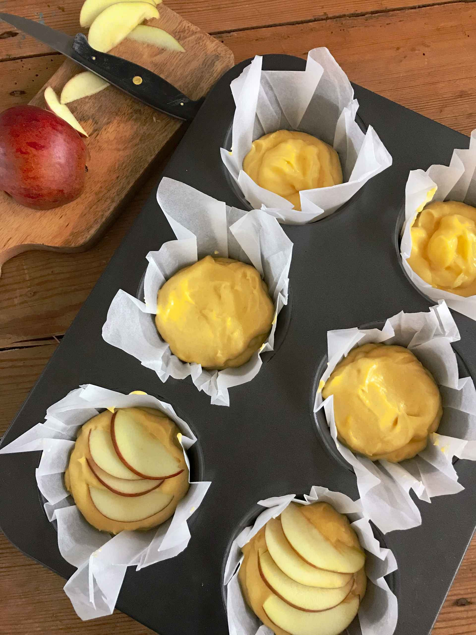 Muffins with apple and custard in a muffin tin.