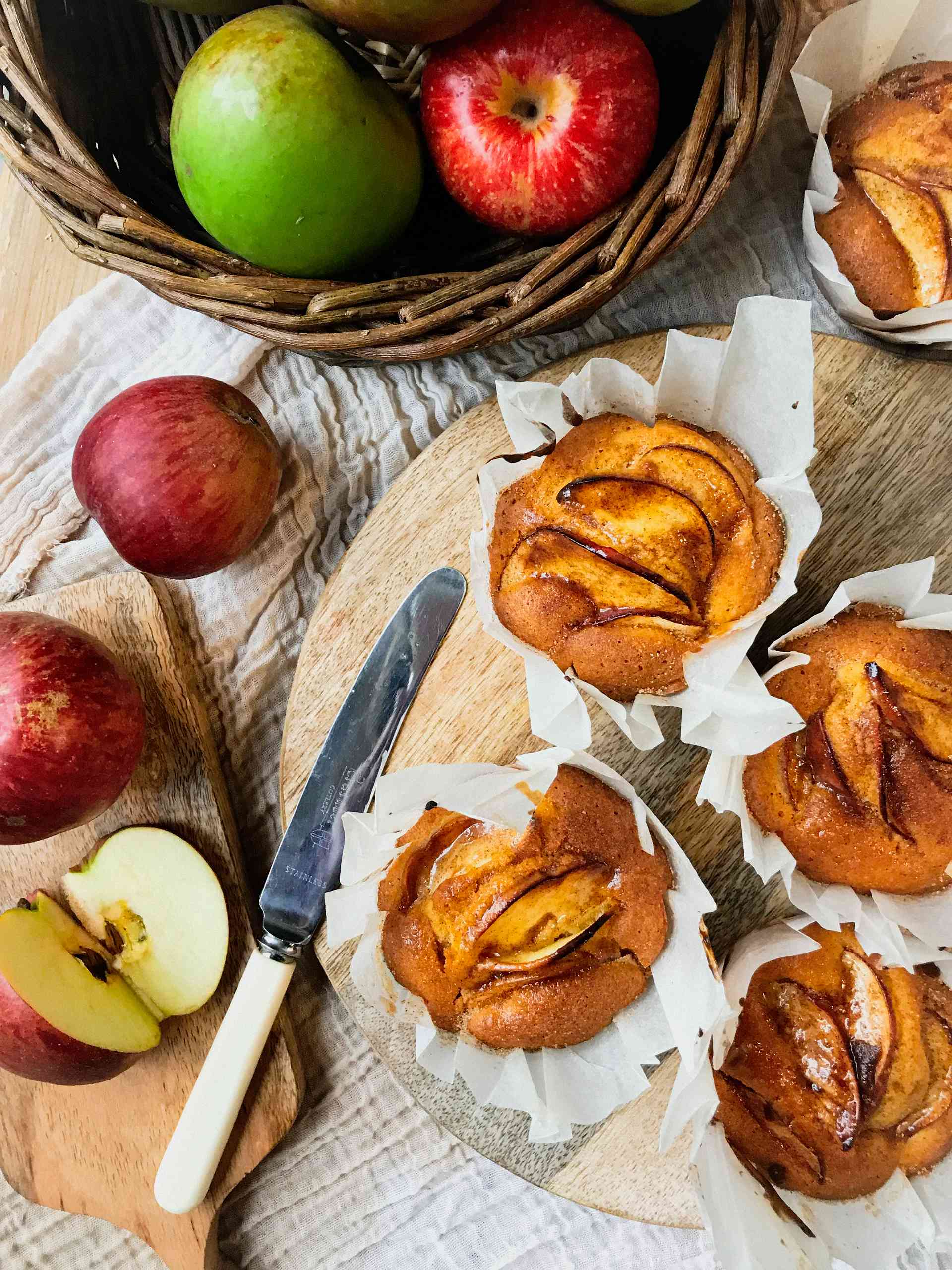 Muffins with apple and custard in a muffin tin with apples on the side.