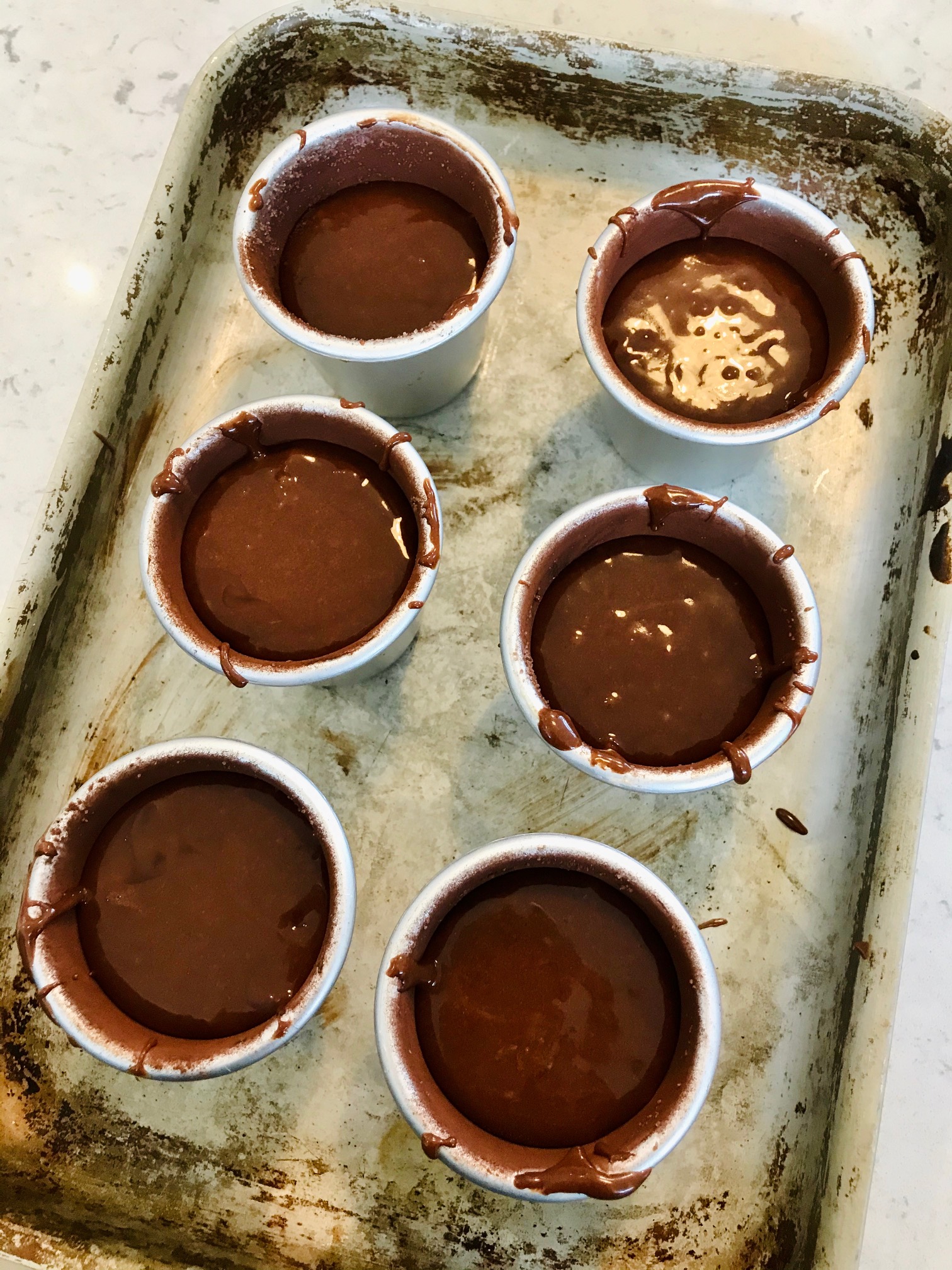 Melting chocolate fondants in cups on a plate.