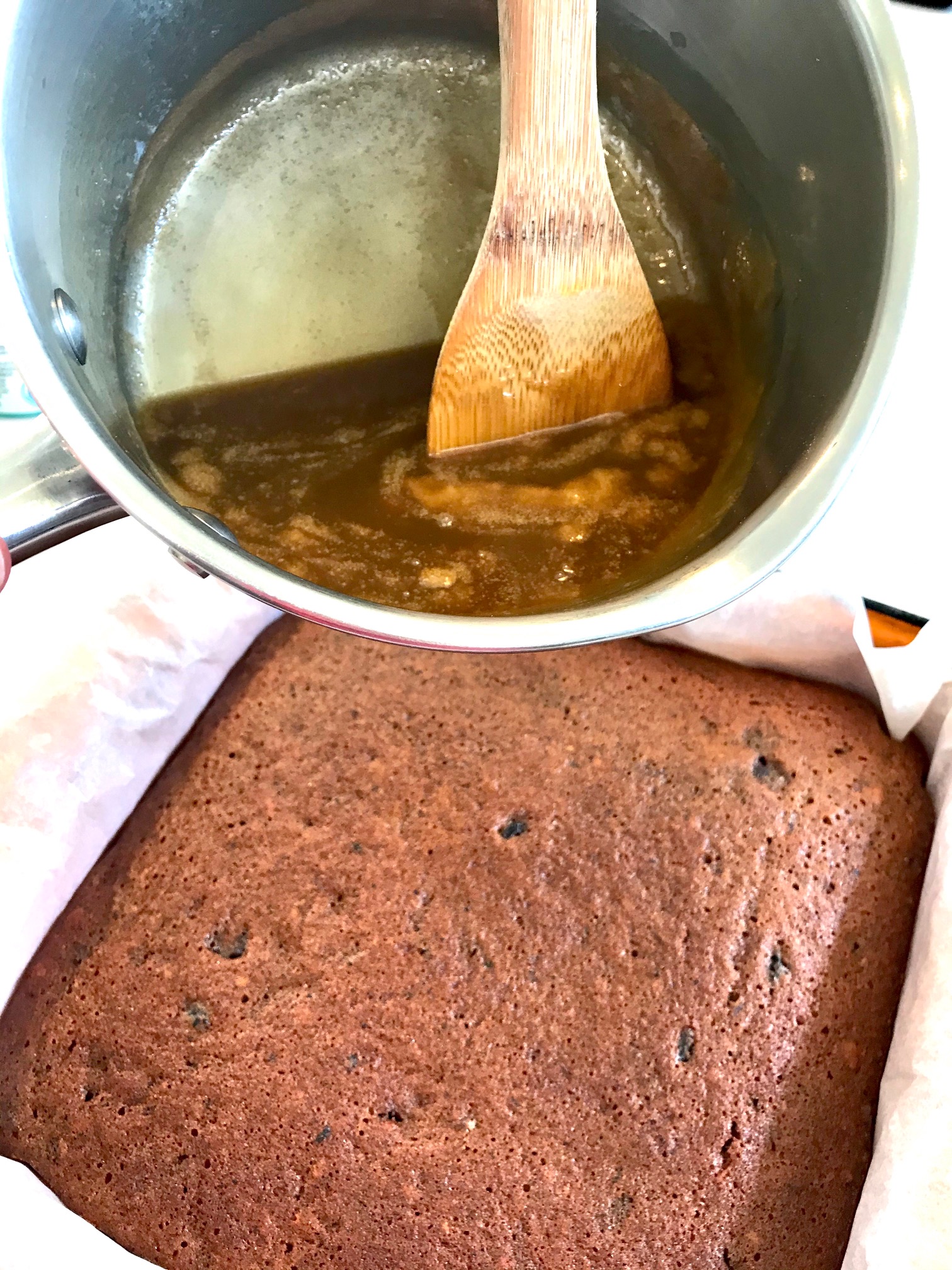 Sticky toffee pudding cake in a cake pan is getting glazed.