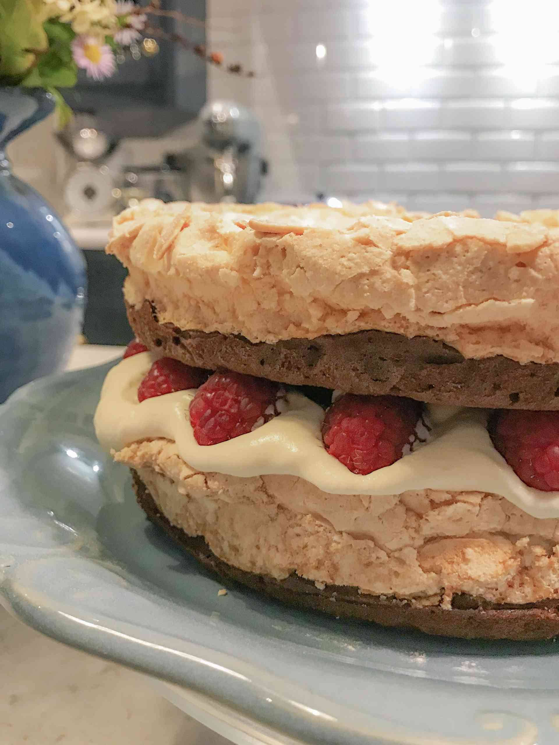 Chocolate and meringue layer cake on a plate on a kitchen countertop.