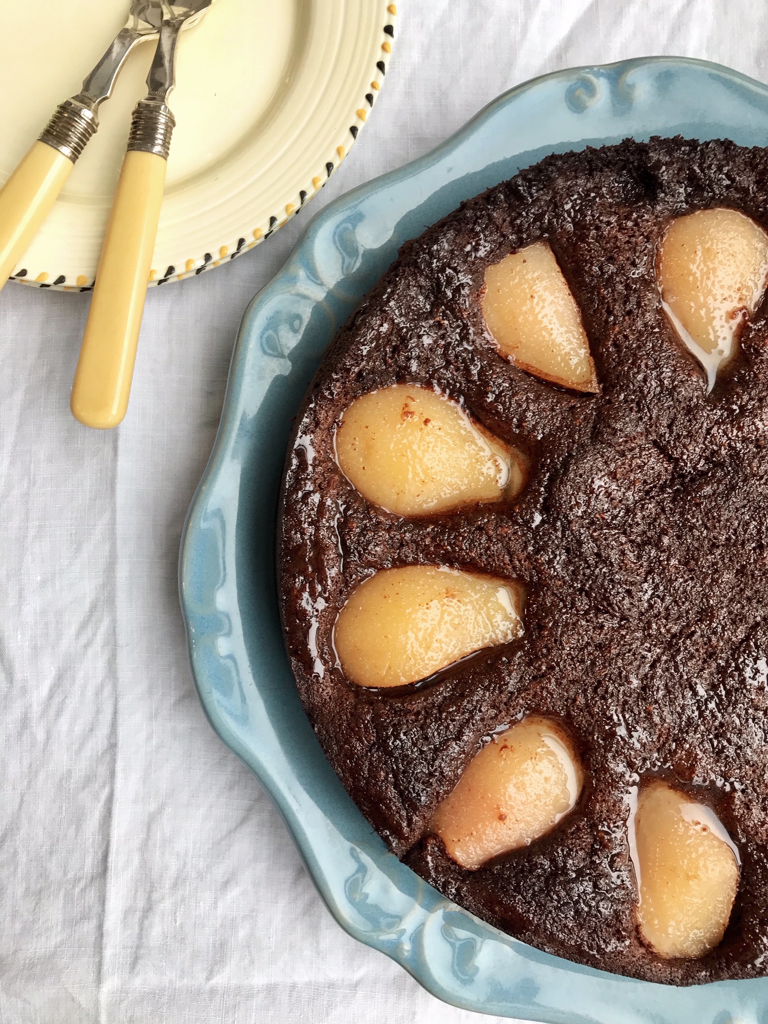Flourless chocolate and pear cake on a plate on a table.