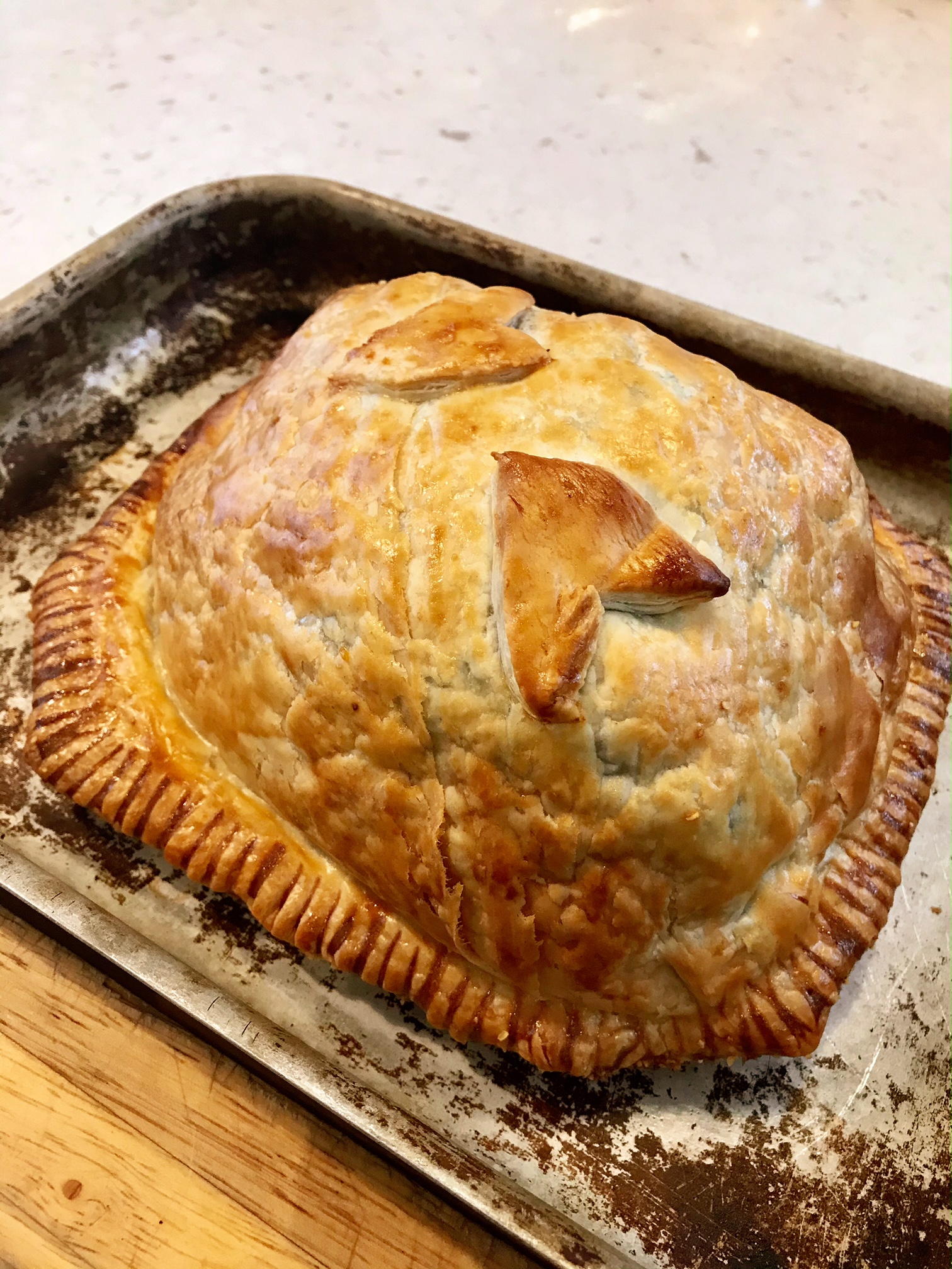Beef wellington on an oven plate on a kitchen countertop.