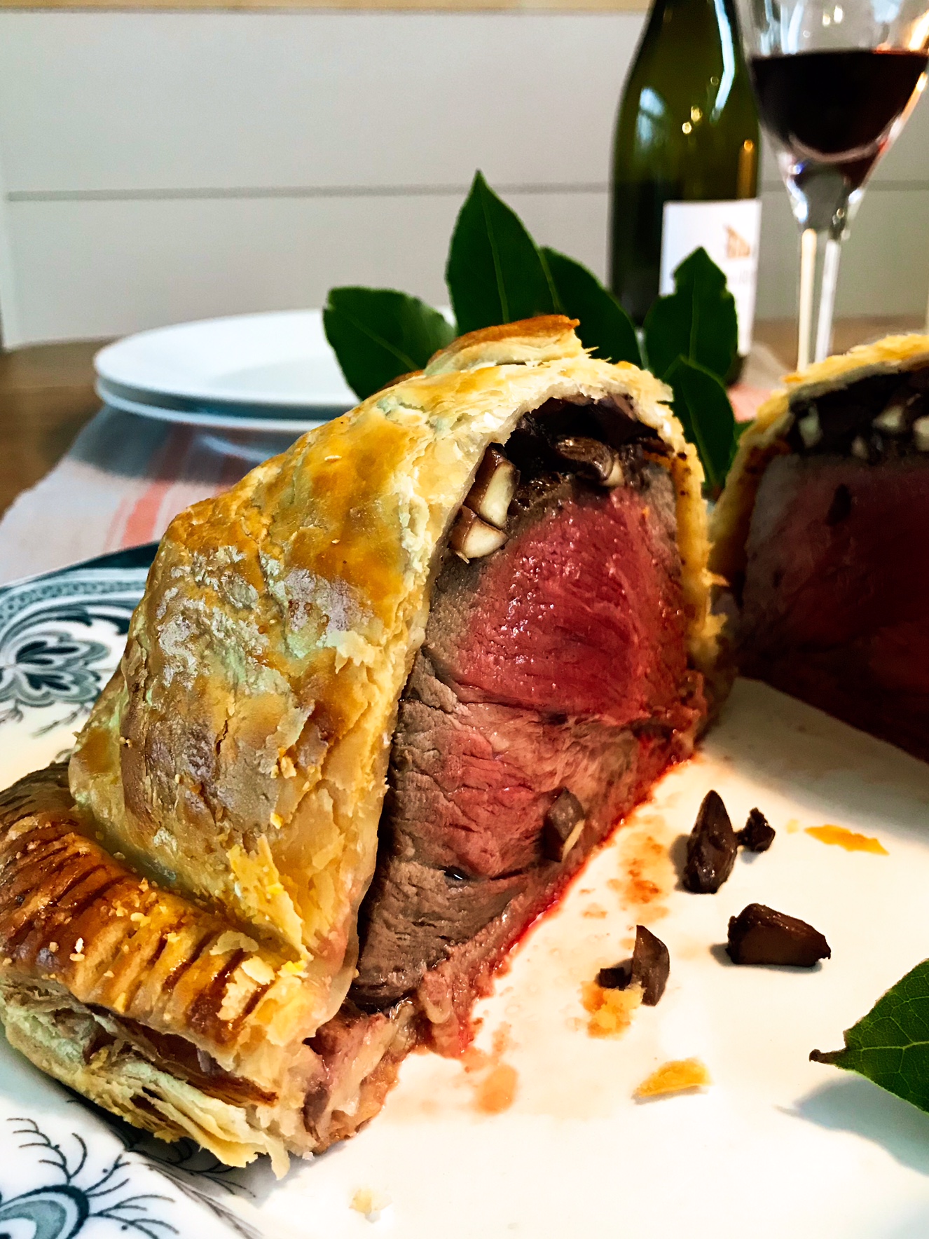 Beef wellington cut in half on a plate on a wooden table.