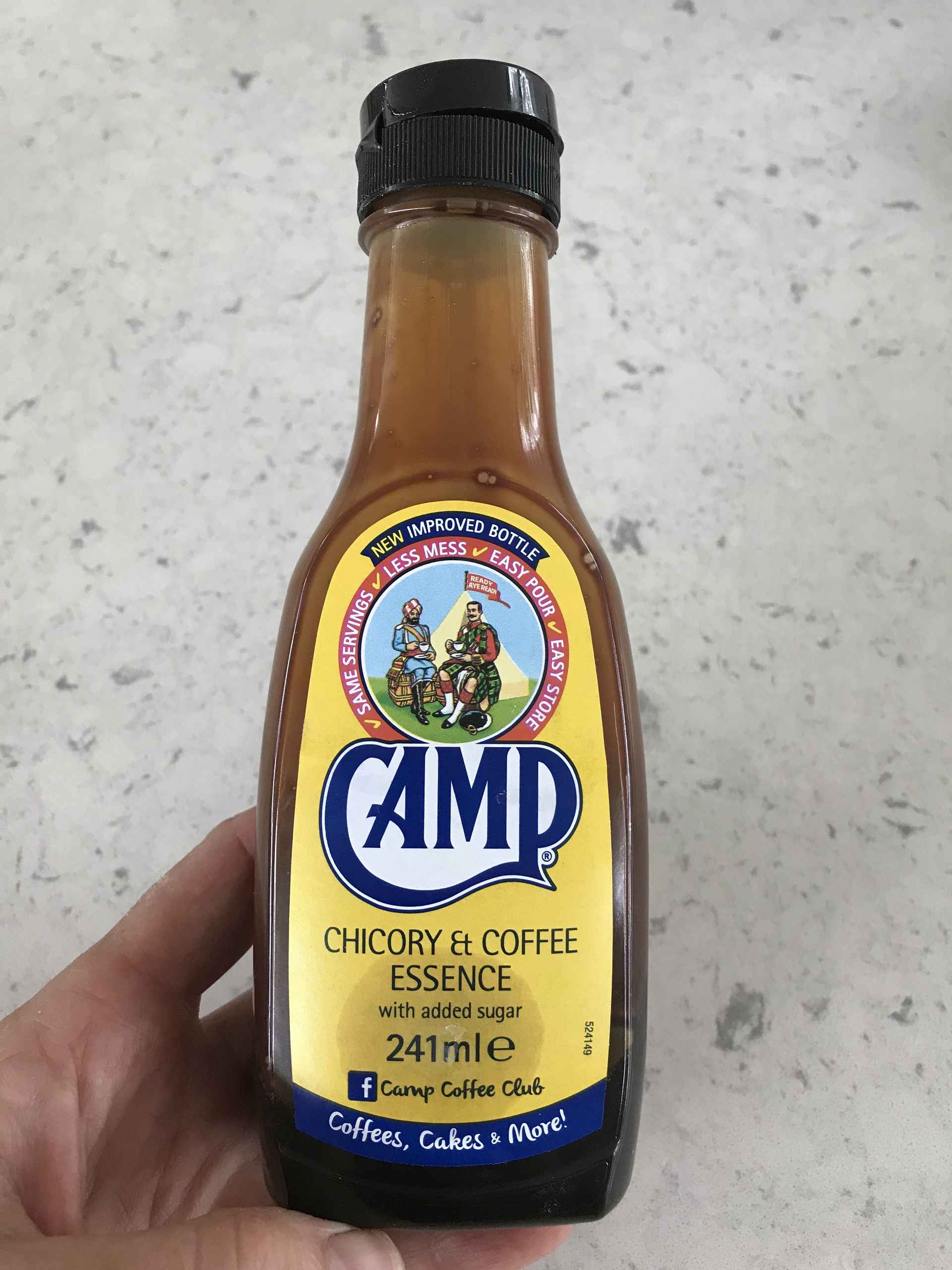 Camp chicory and coffee essence held by someone above a kitchen countertop.