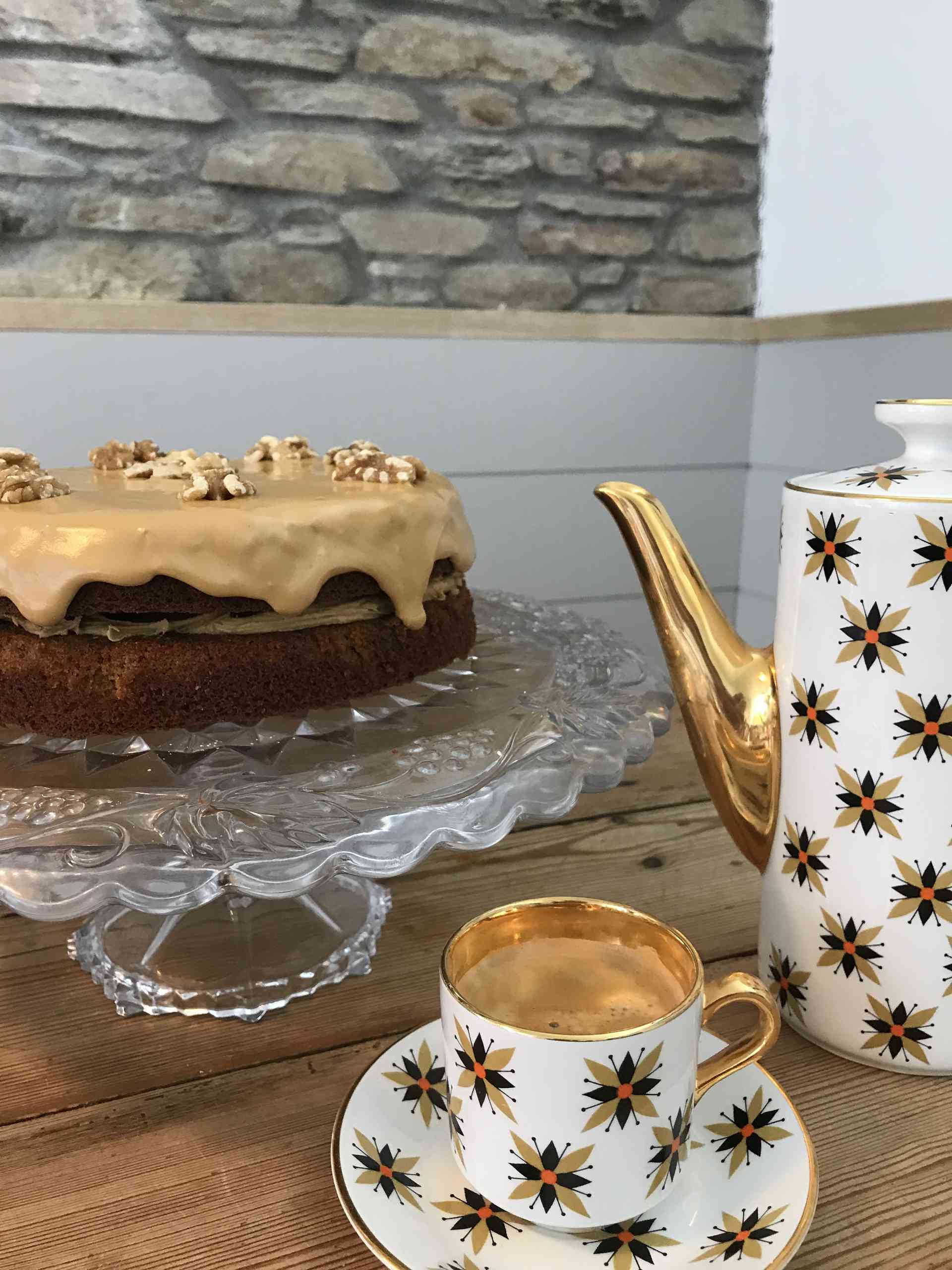 Coffee cake on a glass plate with a cup of coffee beside.